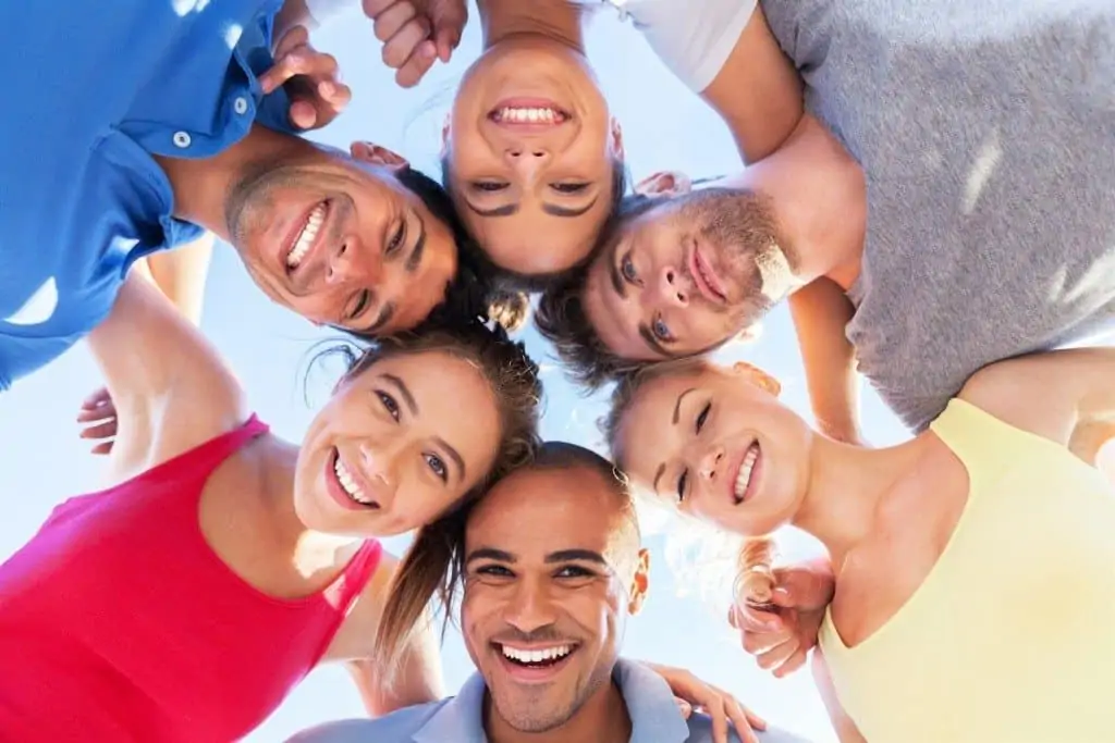 Un groupe de personnes debout en cercle et souriant.