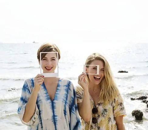 Deux femmes tenant un cadre photo sur la plage.